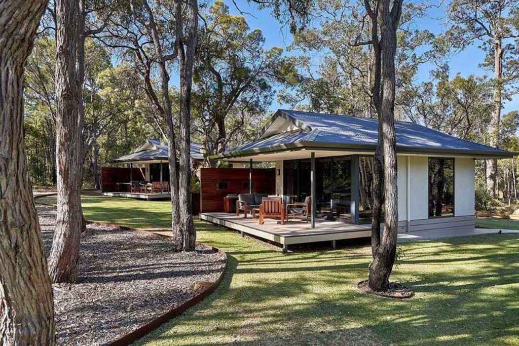 Two small cabins on a grassy area surrounded by Australian native trees