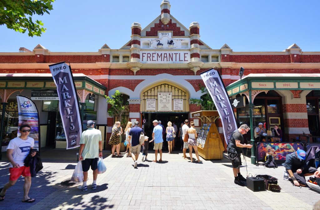 People gathered around a red brick building with a white 'Fremantle' sign on it.