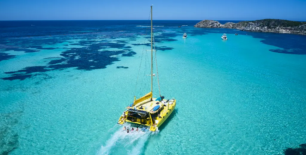 A yellow catamaran cruising through the clear water of Rottnest Island